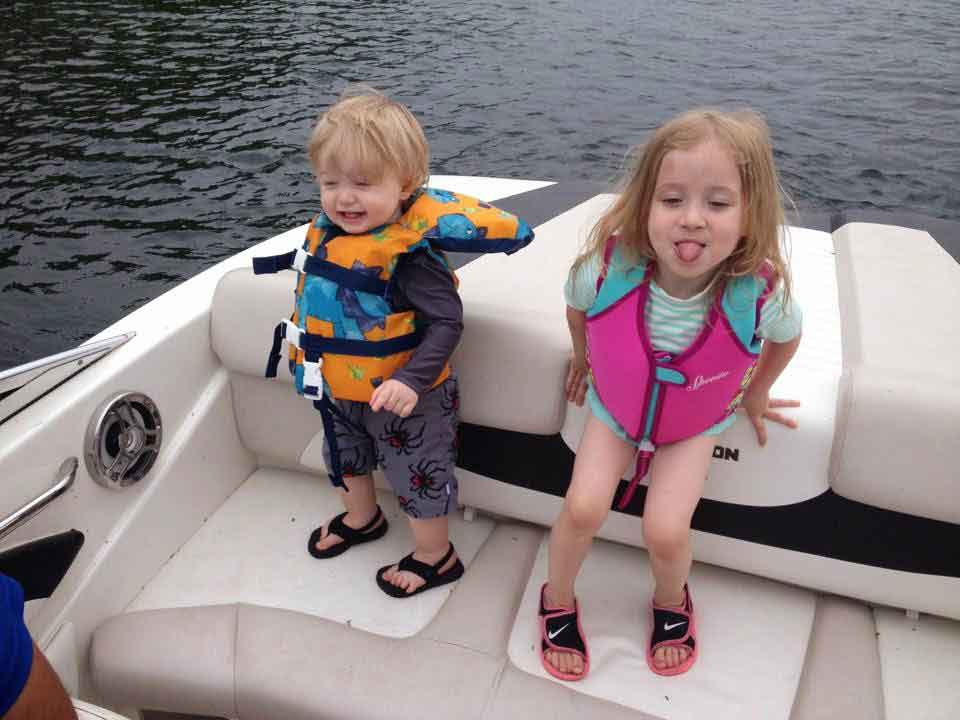 Shawn Jones' kids stand smiling in lifejackets in the back of a boat