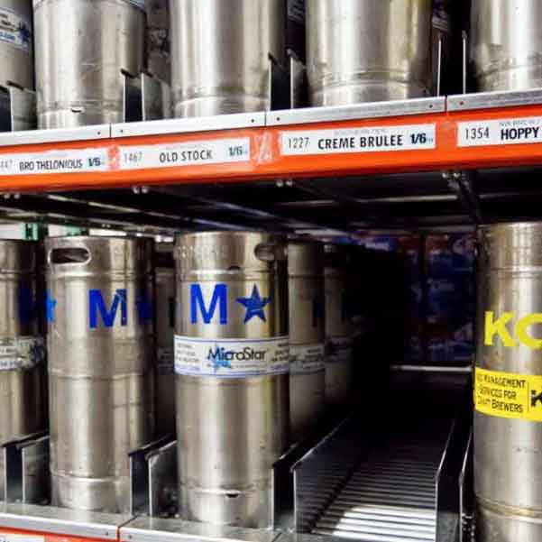 Kegs are stored on keg flow racking with the Unex logo in the bottom right corner