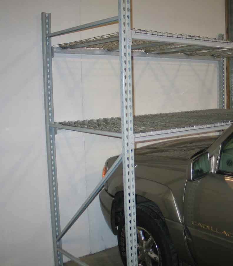 A car is parked and the hood of it sits underneath a pallet rack bay.