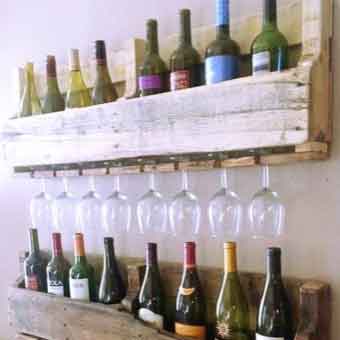 Pieces of pallet racking repurposed to make a shelf that holds wine, and wine glasses hang upside down underneath