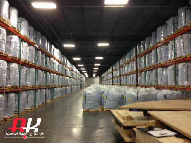An aisle is surround by two 4-level high pallet racking that is filled with materials