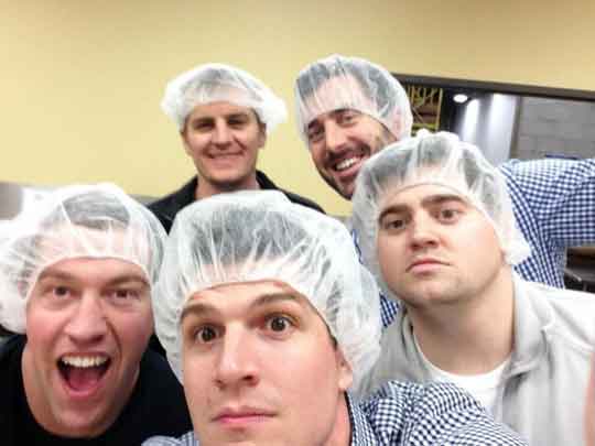The AK team in hairnets smiles at the camera as they volunteer