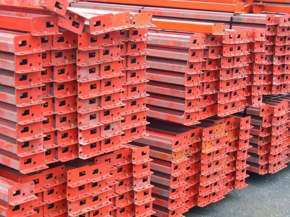 Pallet Rack beams sit in a warehouse piled high on top of one another