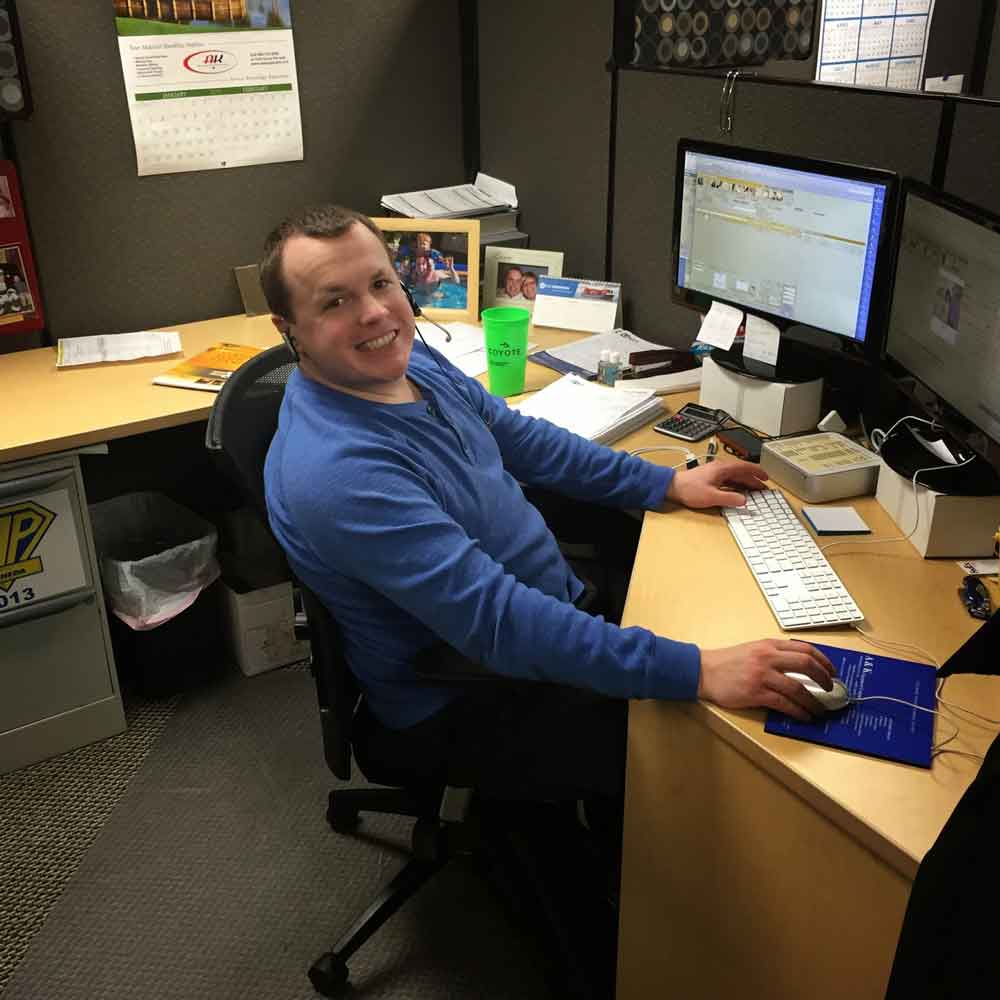 AKMHS employee Matt Johnson smiles at his desk