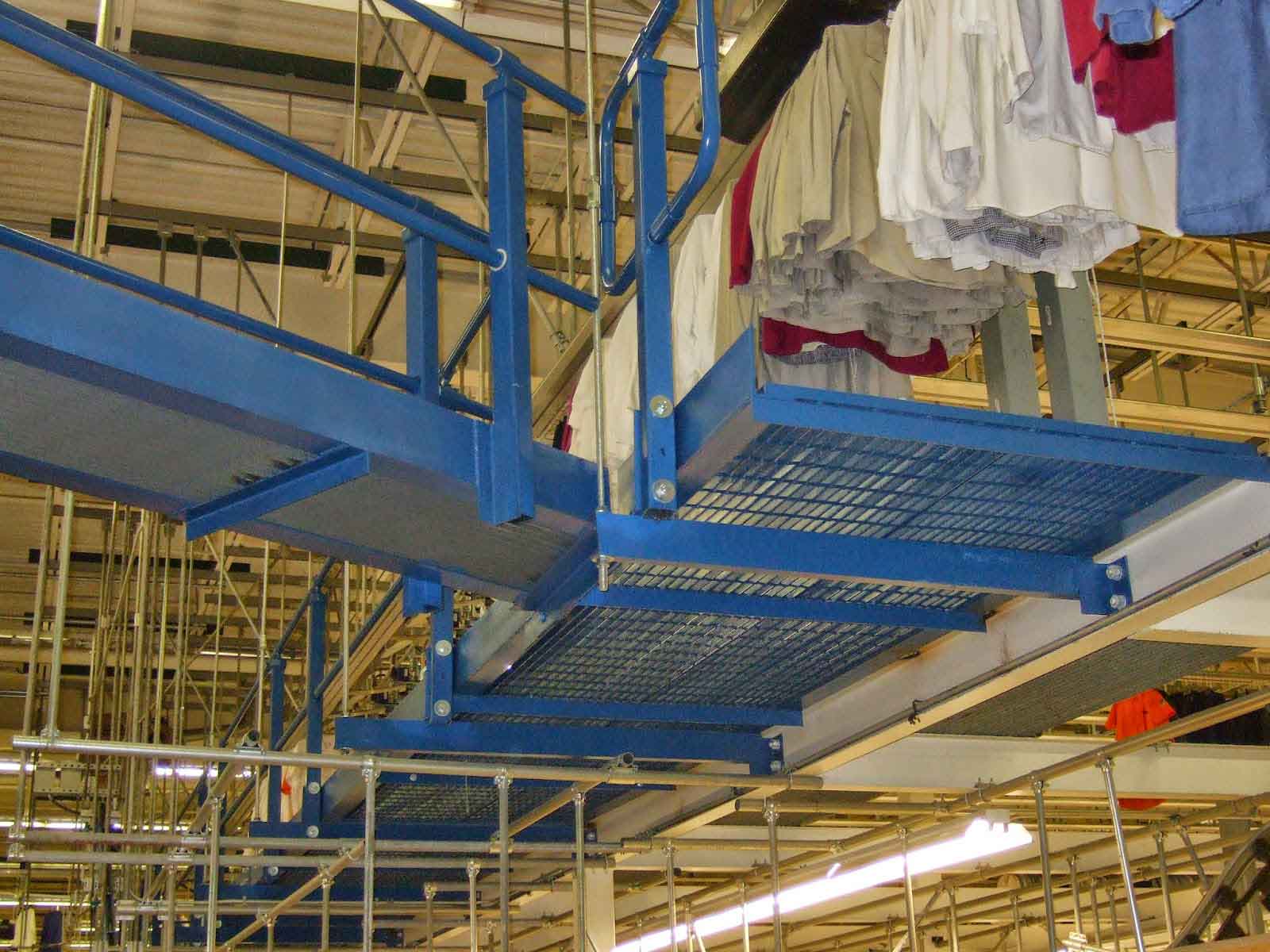 A work platform sits above the ground level of a work area with an automated clothing rack that goes above it