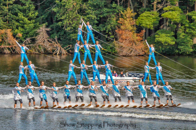 3 pyriamids of people on waterskis smile and wave. The two outer pyramids are smaller than the middle.