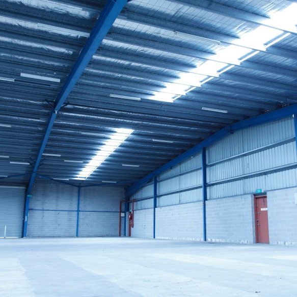 Empty warehouse with high ceilings and an orange door