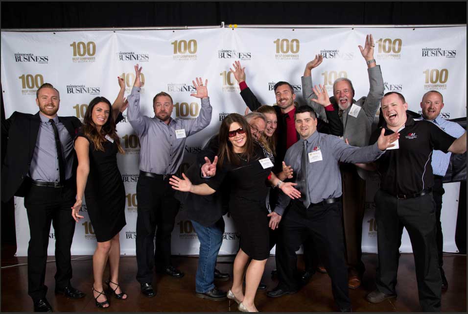 AK Employees smile as and hold their arms up in celebration as they attend the event for Minnesota's best 100 Companies To Work For