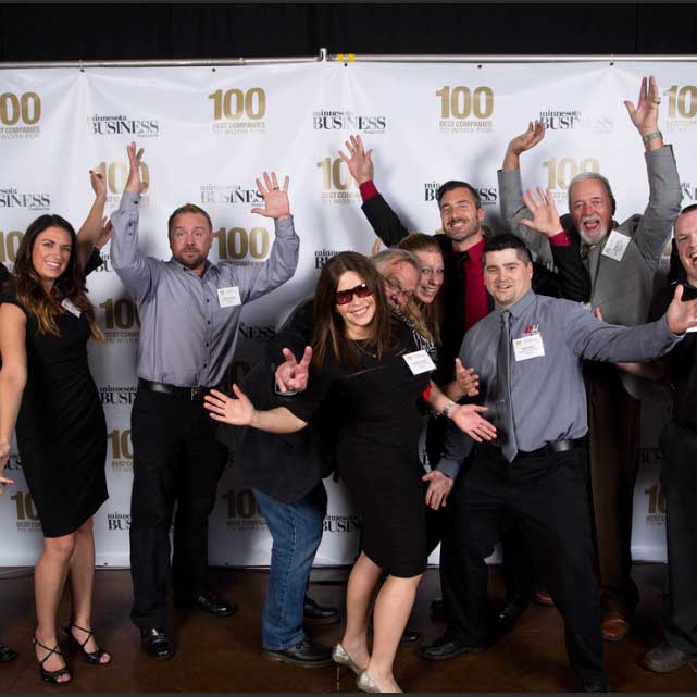 AK Employees smile as and hold their arms up in celebration as they attend the event for Minnesota's best 100 Companies To Work For