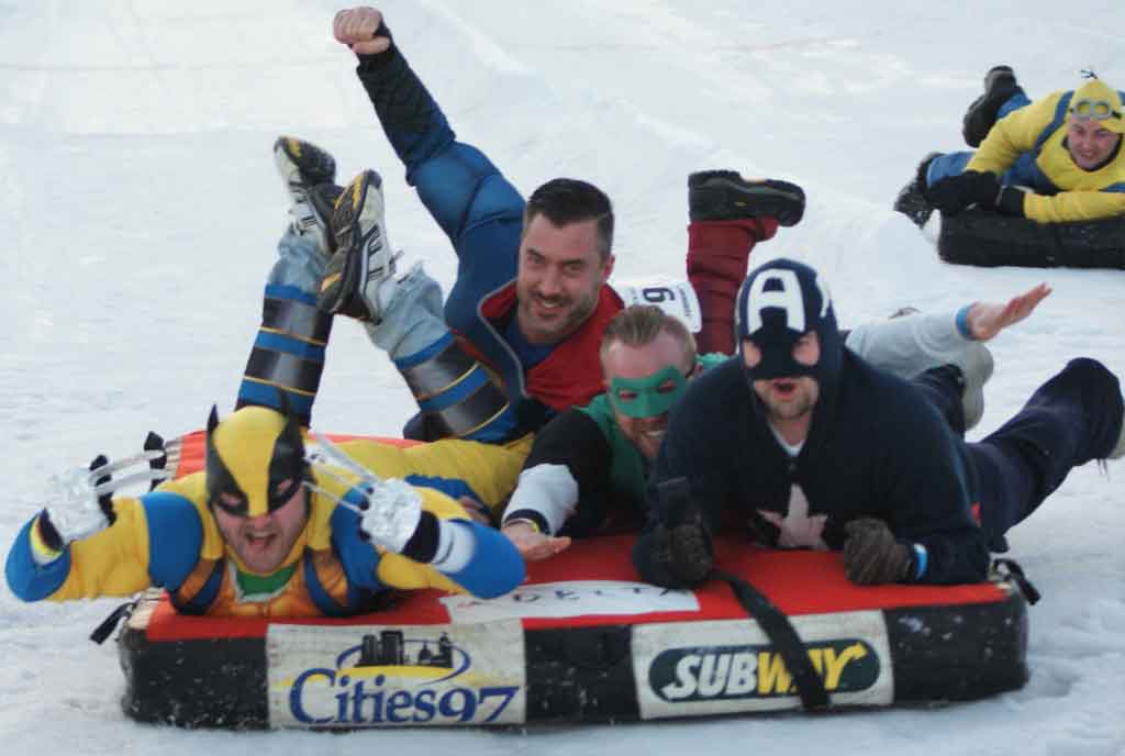 AKMHS Employees dressed as popular super heroes ride a bed like a sled down a hill