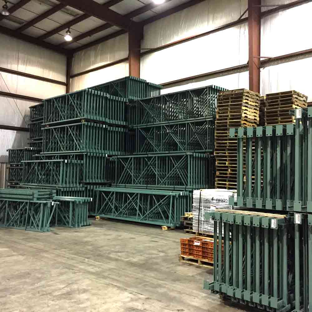 Green pallet rack frames sit stacked on top eachother of the corner