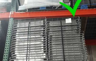 Wire decking stored on a wooden pallet on selective pallet racking with a bright green check mark over the top right corner of the image