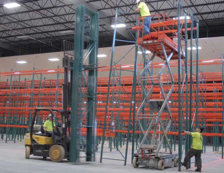 Installers installing selective pallet racking using a forklift and scissor lift