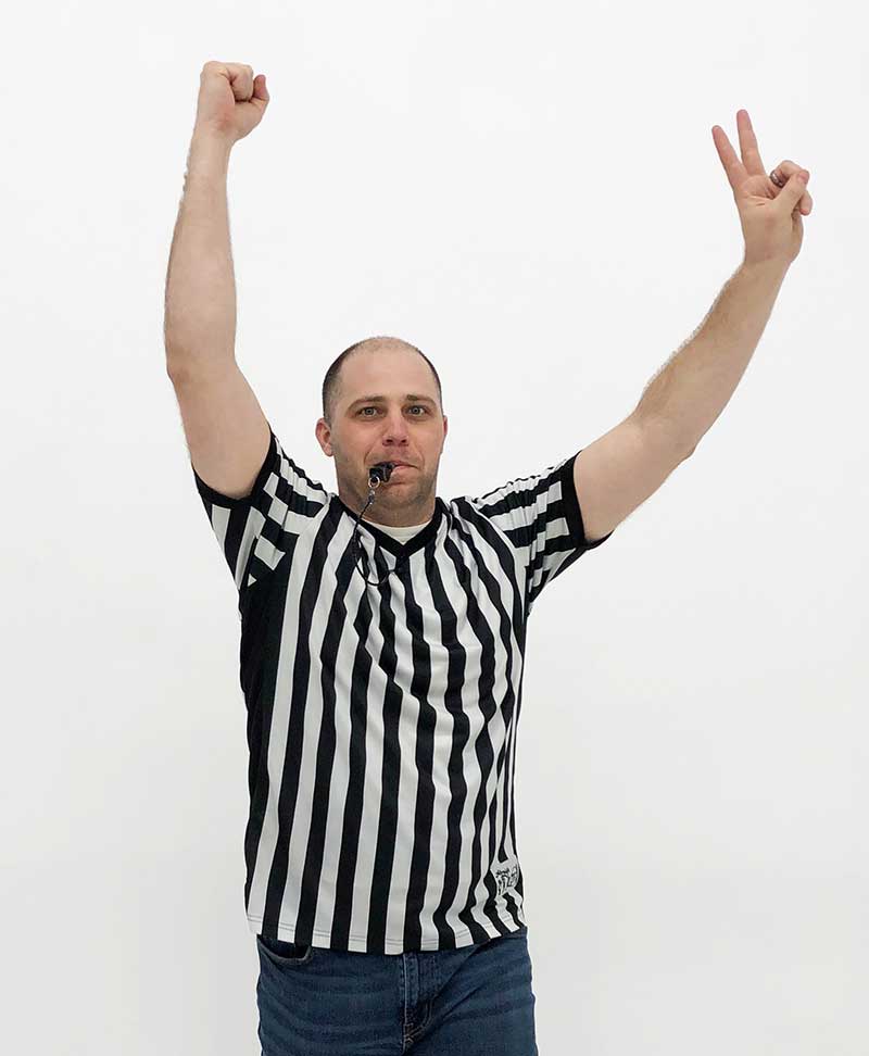 a ref with a whistle in his mouth holding up a zero in one hand and a two in the other
