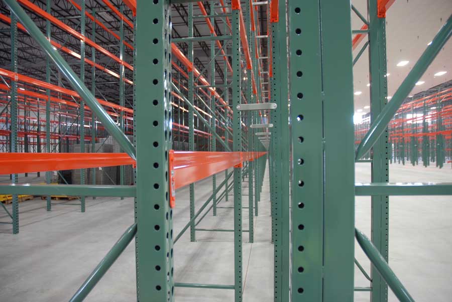 An up close picture of pallet racking in Bunzl’s distribution warehouse. Beams and frames over lap eahother and in the back left corner a stack of wire decking can be seen sitting on a wooden pallet.