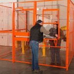 Worker greeting someone through an orange Beastwire warehouse security cage otherwise known as a drivers cage.