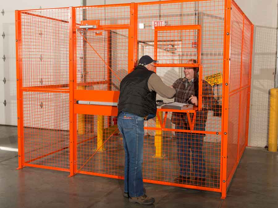 Worker greeting someone through an orange Beastwire warehouse security cage otherwise known as a drivers cage.